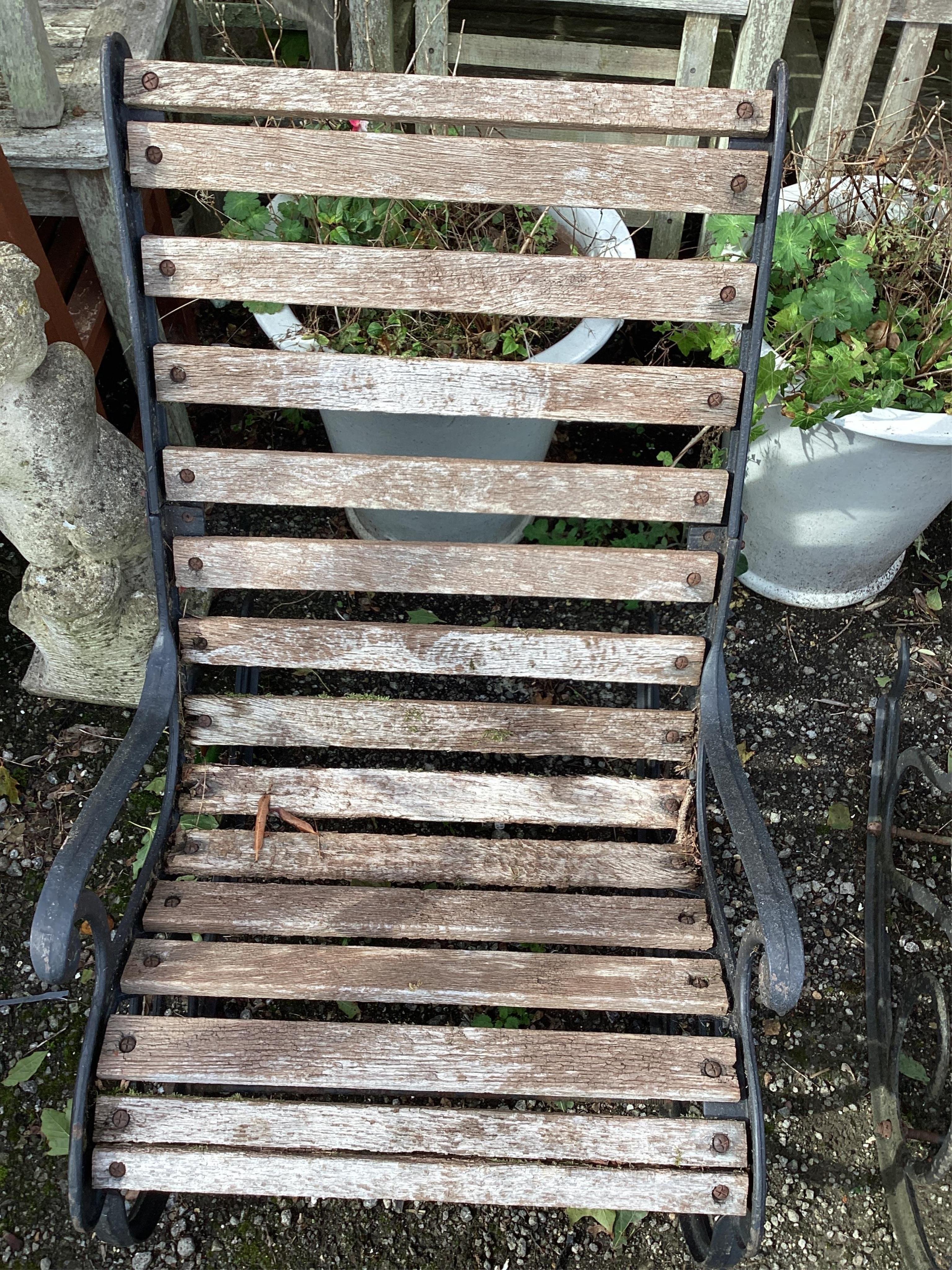 A pair of slatted cast metal garden rocking chairs